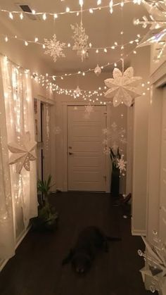 a hallway decorated for christmas with lights and snowflakes hanging from the ceiling above