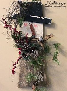 a snowman made out of burlocks and pine cones is hanging on the wall