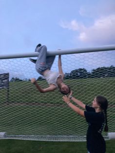 two people reaching for a soccer ball in front of a goal