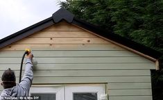 a man is painting the side of a house