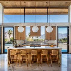 an open kitchen and dining area with wooden cabinets, marble counter tops and stools