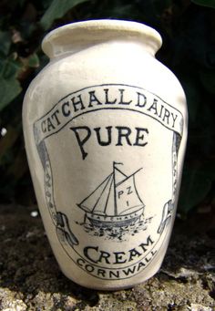 a white ceramic jar with the words catchall dairy pure on it and a sailboat