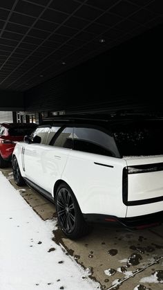 several cars parked in a parking garage with snow on the ground and one is white