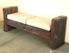 a wooden bench sitting on top of a floor next to a white wall with a black frame