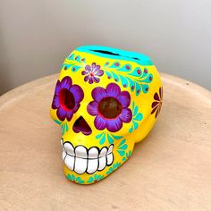 a yellow and blue sugar skull sitting on top of a wooden table