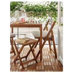 a wooden table with two chairs and a plant in the window sill behind it