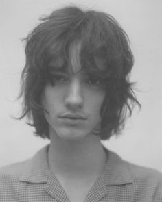 black and white photograph of a young man with wavy hair wearing a button up shirt