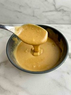 a spoon full of peanut butter in a bowl on a marble counter top with a marble background