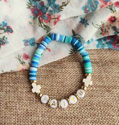 a bracelet with beads and charms on top of a fabric covered table next to a flowered cloth