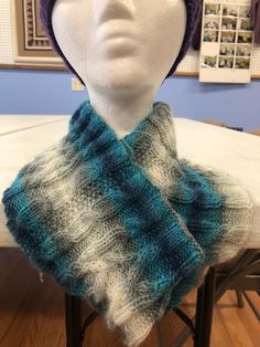 a white mannequin head wearing a blue and gray knitted cowl scarf