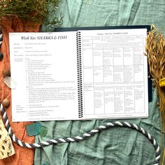 an open spiral notebook sitting on top of a table next to flowers and other items