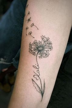 a dandelion tattoo with the word love written in cursive writing on it