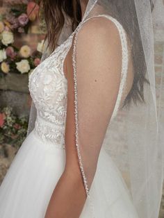 the back of a bride's wedding dress, with her veil draped over her shoulder