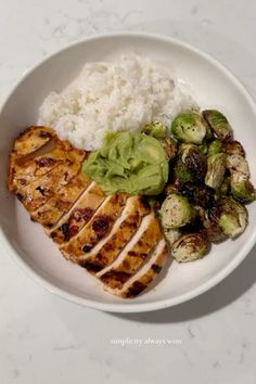 a white plate topped with chicken, brussel sprouts and rice