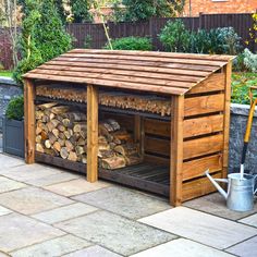 an outdoor firewood storage shed with logs stacked in it and a watering can next to it