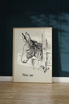 a black and white drawing of a horse in a frame on the floor next to a wall