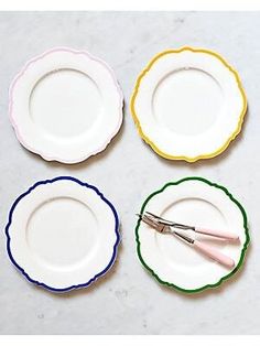 four plates with different colored trimmings and one is holding a pair of scissors