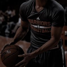 a man holding a basketball in his right hand and wearing a black shirt with warriors on it