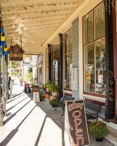 the sidewalk is lined with potted plants and signs that read, alleyway cafe