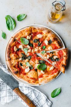 a pizza on a plate with several slices cut out and sitting next to a glass of beer