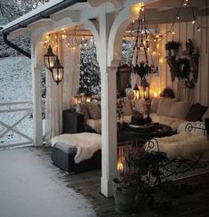 an outdoor living room with lights on the ceiling and furniture in the snow covered area