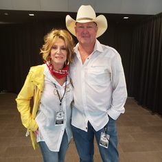 a man and woman standing next to each other in front of a black curtained room