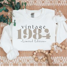 a white sweatshirt with the words vintage 1994 printed on it next to some wood beads