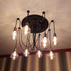 a chandelier with many bulbs hanging from it's ceiling and some lights on