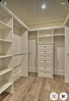 an empty walk in closet with white shelves and drawers