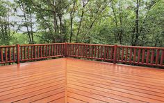 a wooden deck with railings and trees in the background