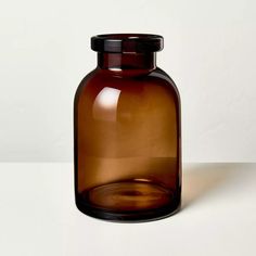 a brown glass bottle sitting on top of a white table next to a black lid