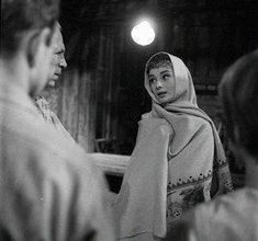 an old photo of two women talking to each other in front of a group of people