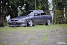 a grey car parked in front of some trees