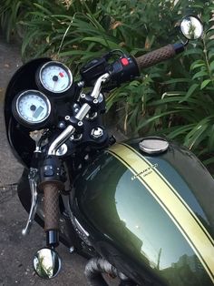 a close up of a motorcycle parked on the side of the road near some bushes