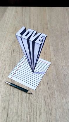 an origami kite sitting on top of a wooden table next to a pen