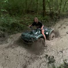 a woman riding on the back of an atv through mud