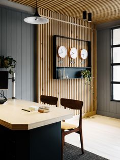 a table with two chairs in front of it and clocks on the wall behind it