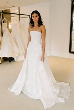 a woman standing in front of some wedding dresses