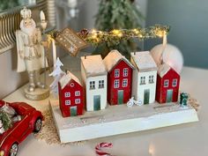 a red car is parked in front of a christmas village