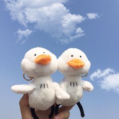 two white stuffed birds sitting on top of each other in front of a blue sky