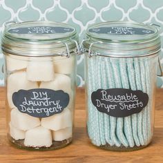 two jars filled with marshmallows on top of a wooden table