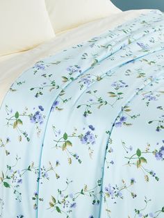 the comforter is made up with blue and purple flowers on it, along with white pillows