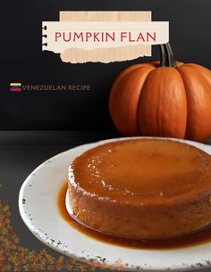 a cake sitting on top of a white plate covered in caramel sauce next to a pumpkin