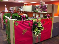 an office cubicle decorated with pink and green christmas decorations, wrapped in red paper