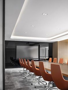 an empty conference room with orange chairs and a projector screen in the back ground