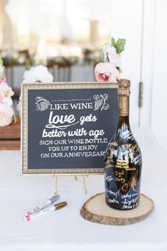 a bottle of wine sitting on top of a table next to a chalkboard sign