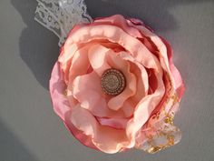 a pink flower with a lace headband on top of a gray table next to a white lace doily