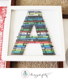 a framed letter made out of books sitting on the floor