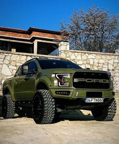 a green truck parked in front of a stone wall