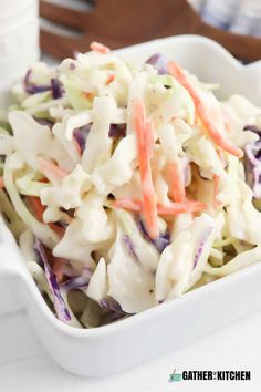 coleslaw salad in a white serving dish with carrots and celery